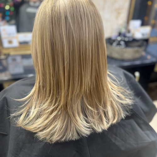 Vedere din spate a unei tunsori pentru femei cu par lung si cu balayage blond natural, par deschis la vârfuri cu reflexe aurii și șaten la rădăcină, realizata la Sia's Beauty Iasi, Lunca Cetatuii,
