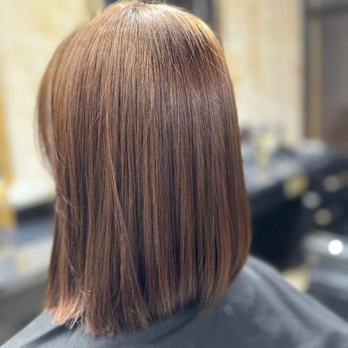 Imagine din spate a unei cliente cu par saten mediu, drept si stralucitor, tuns in forma de bob cu linie dreapta la baza si varfuri uniforme. Parul este bine ingrijit, cu luciu natural si o cadere eleganta. Clienta poarta un halat inchis la culoare de protectie. In fundal se observa interiorul salonului Sia's Beauty din Lunca Cetatuii, cu scaunele si elementele decorative specifice. Imaginea prezinta rezultatul unui tuns femei Iasi realizat cu atentie la detalii.