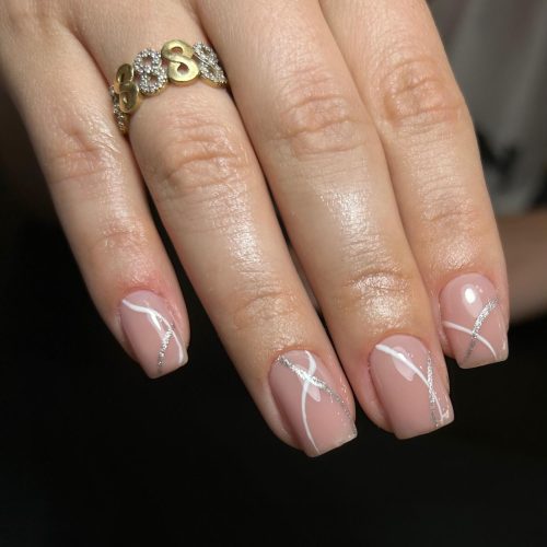 Unghii cu gel cu baza nude si design abstract modern cu linii albe si argintii cu sclipici