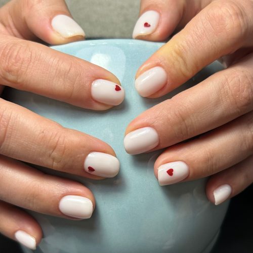 Unghii cu gel nude crem decorate cu inimioare rosii mici pe fiecare unghie